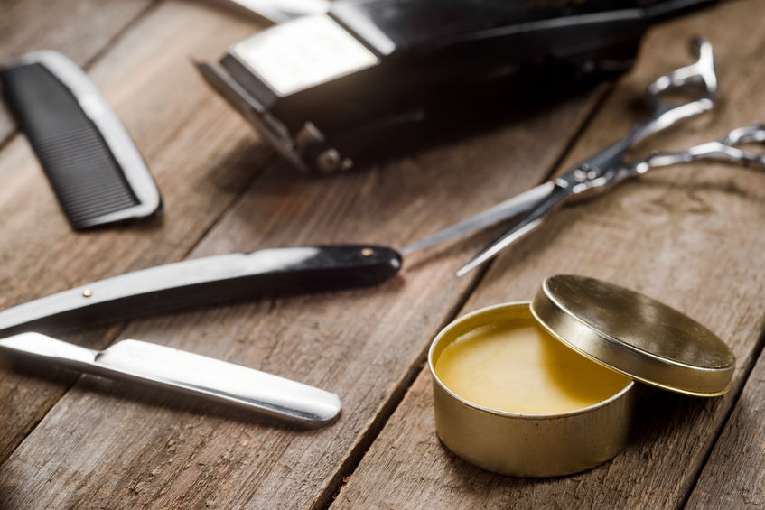 Wax, barber scissors, a straight razor, a comb on the wooden surface