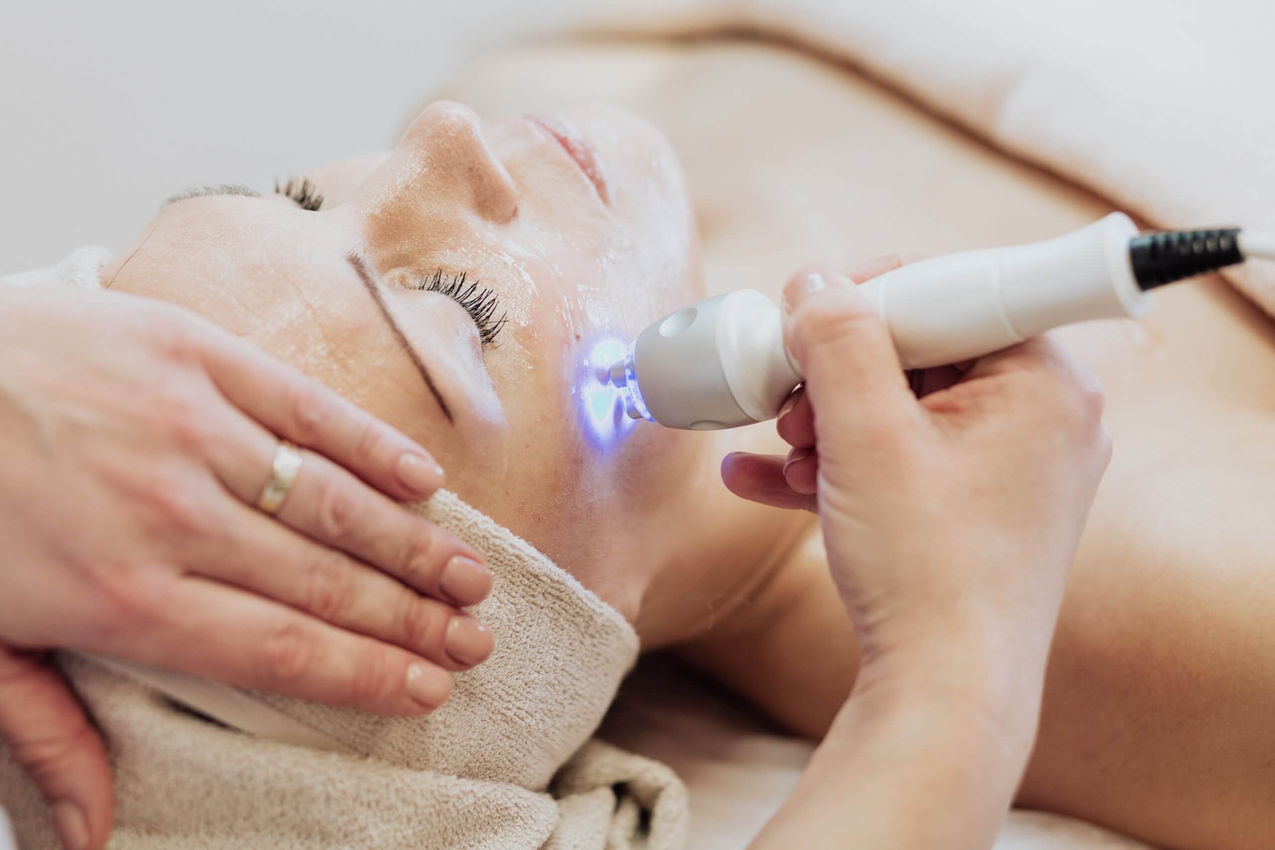 go to a premier laser technician school in chicago to become a laser technician performs cosmetic laser treatment on a woman's face
